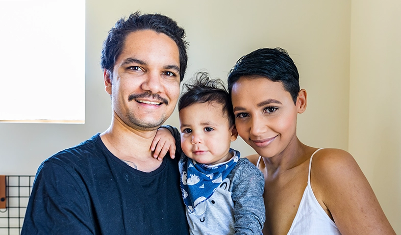 Aboriginal parents holding their young child smiling at the camera