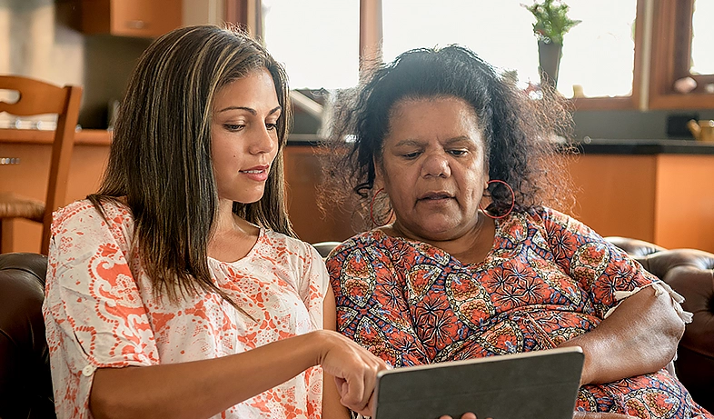 An Aboriginal mother and daughter sitting on a couch discussing secondary school options